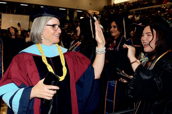Outgoing WHC Chancellor Kristin Clark high fives Lemoore College grads.